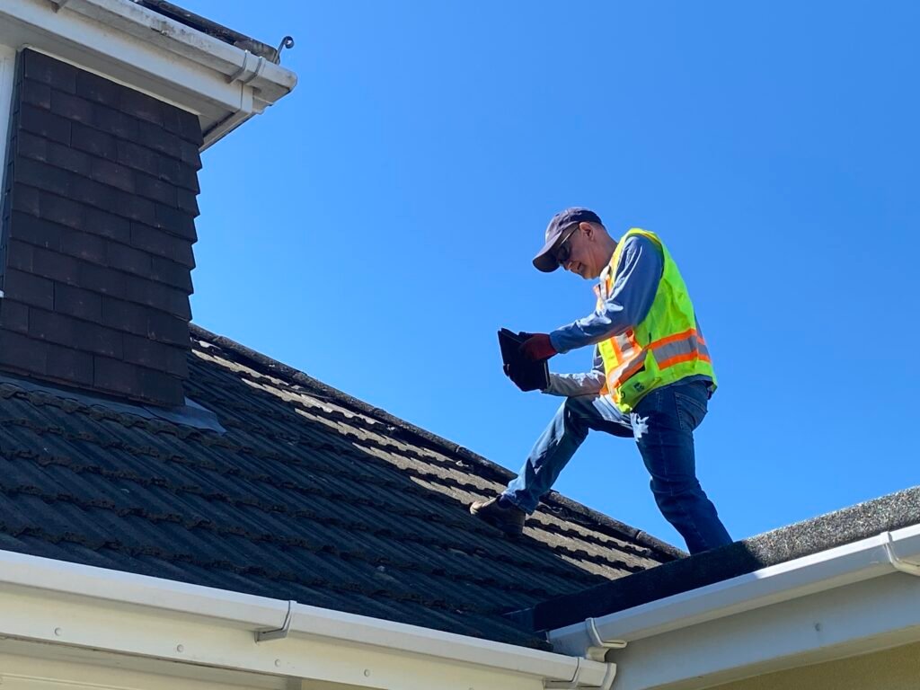 A certified home inspector examining a residential asphalt shingle roof for a property inspection